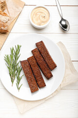 Plate with tasty croutons and sauce on white wooden background