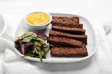 Plate with tasty croutons and sauce on white wooden background