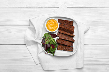 Plate with tasty croutons and sauce on white wooden background