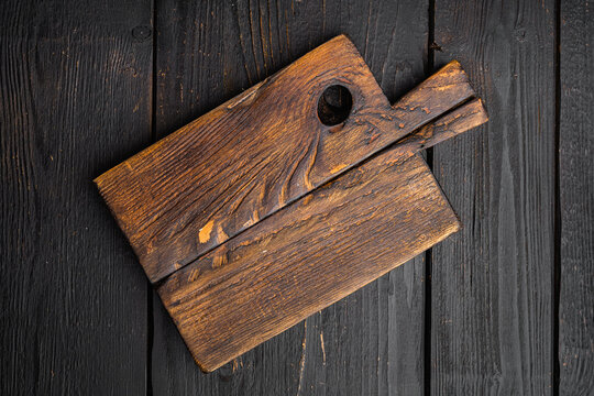 Old wooden kitchen board, top view flat lay , with copy space for text or food, on black wooden table background