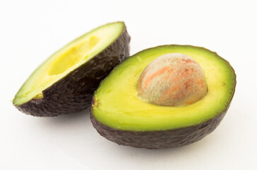 halved avocado with bone on white background