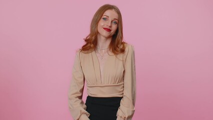 Smiling lovely businesswoman girl in beige blouse makes sign heart shape gesture demonstrates love expresses good feelings and sympathy. Young adult woman isolated alone on pink studio background