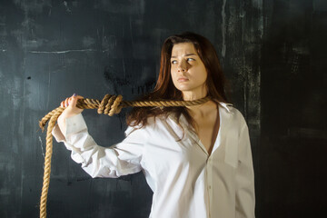 Portrait of a young woman with a rope loop and emotions despair, longing, depression, fear, loneliness, psychopathy, hopelessness
