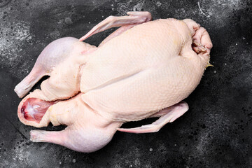 Fresh raw whole duck ready for cooking, on black dark stone table background, top view flat lay