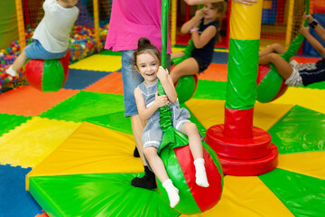 Fototapeta na wymiar Girl rides on a carousel in a children's play center