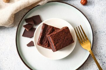 Plate with pieces of delicious chocolate brownie on light background