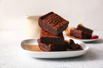 Plate with pieces of delicious chocolate brownie on light background