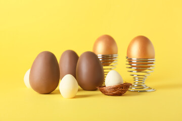 Different chocolate Easter eggs on yellow background
