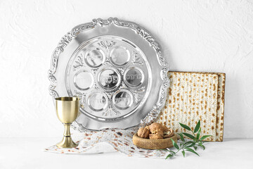 Passover Seder plate with cup of wine, walnuts and matza on white background