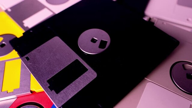 vintage retro electronic data storage devices, from the 80s, 90s flash drives scattered on the table. Stack of floppy disks, pendrive and hard disk in grey, black, blue, yellow, red, white