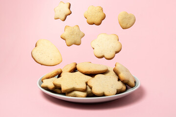 Cookies fall into a plate with cookies on a pink background. Homemade shortbread cookies. Delicious and light dessert.