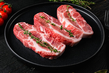 Fresh pork neck meat steaks, on black wooden table background