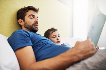 Fototapeta premium Nobody does story time like dad does. Shot of a young man reading a book with his son at home.