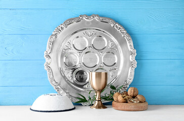 Passover Seder plate with cup of wine, kippah and walnuts on table against color wooden background - obrazy, fototapety, plakaty