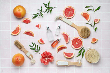 Bottles of grapefruit oil with bathing supplies on color background