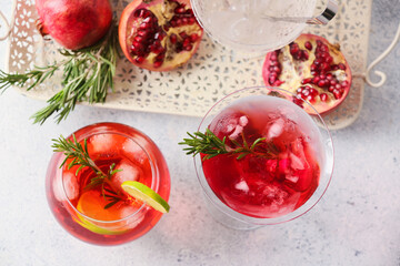 Fototapeta na wymiar Glasses of tasty pomegranate cocktail on light background