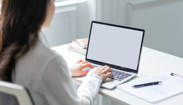 Image of young Asian business woman using laptop with blank screen
