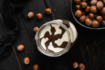 Chocolate spread or nougat cream with hazelnut, on black wooden table background, top view flat lay