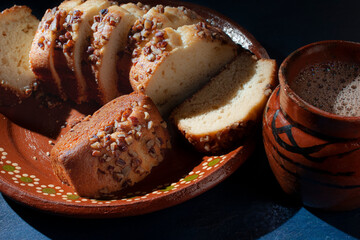 Slices of sweet bread with pieces of walnuts on top, over a mud or clay mexican plate and a blue surface table, overhead, top view flat lay horizontal macro photography.