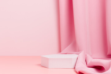 Geometric empty podium with textile fabric drape on pink background, display for product, cosmetic and perfume presentation