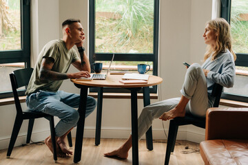 Young woman and man sitting at a table at home using  wireless devices for work and social media.