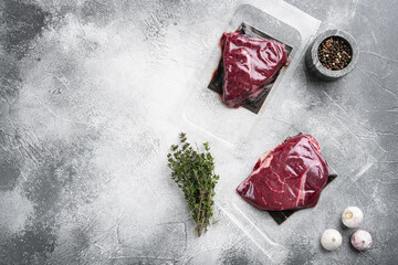 Beef steak vacuum sealed, on gray stone table background, top view flat lay, with copy space for text
