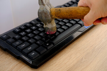 closeup computer keyboard, iron hammer hits keys with force, breaks gadget, concept annoys slow...