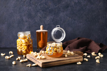 Fototapeta na wymiar Jars of sweet cashew nuts in honey on dark background