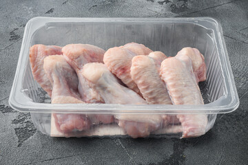 Fresh chicken wings spit in plastic vacuum pack, on gray stone background