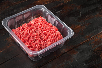 Raw Minced Meat in a transparent Plastic Container, on old dark  wooden table background, with copy space for text