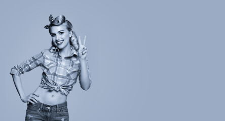 Portrait of beautiful young happy smiling woman, showing two fingers or victory gesture, pin up style. Caucasian blond girl posing in retro fashion and vintage concept. Black and white. Copy space.