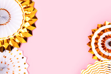 Border frame made of gold colored paper fans on a pink background.