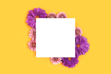 Empty paper card mockup with border frame made of purple dahlia flowers on a yellow background. Springtime concept with copyspace.