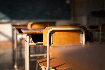 Empty Japanese school classroom with wooden chairs, desks, and a chalkboard. 