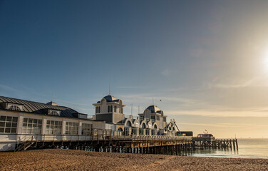 Seaside pier against a shingle beach.  Taken on a bright day with strong afternoon lighting.
