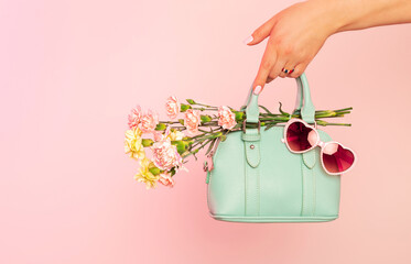 Fashion spring accessories - mint handbag (purse) and heart shaped sunglasses on pastel pink.