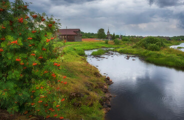 The historic village of Pyalma in Republic of Karelia on the river bank during summer evening rain - obrazy, fototapety, plakaty