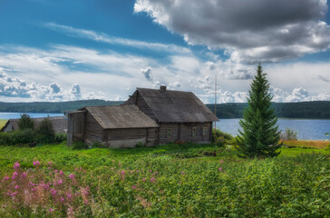 Old wooden log house on the shore of lake in northern summer