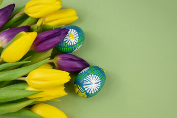 Beautiful hand painted easter eggs with yellow and purple tulips frame stock images. Easter colored eggs isolated on a green background with copy space for text stock photo. Spring easter eggs border