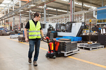 Warehouse worker dragging hand pallet truck or manual forklift with the shipment pallet unloading...