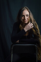 Portrait of a beautiful young woman with very long hair who is smiling sitting on a stool