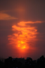 Sun behind the cloud at sunset bonfire-like vertical photo