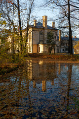Historyczny park pałacowy jesienią z widocznymi budynkami mieszkalnymi i gospodarczymi. - obrazy, fototapety, plakaty