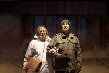Elderly wife and husband standing together in a nuclear shelter