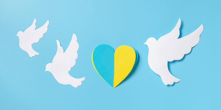 The paper heart is the flag of Ukraine and the white dove of the world on a blue background. Top view. No war concept