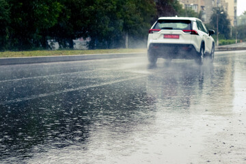 The car is driving on the road during heavy rain. Summer rain on the track