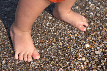Boy's feet on wet sea sand. Summertime holidays concept. Close-up