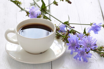 Cup of coffee tea chicory drink with chicory flower on a white table - obrazy, fototapety, plakaty