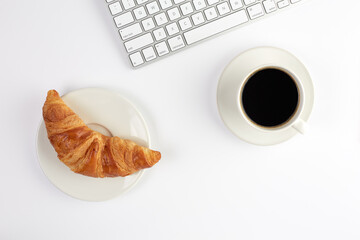 Top view of keyboard, croissant and cup of coffee on white background