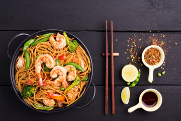 Stir-fried spaghetti or stir-fry noodles with vegetables and shrimp in a black bowl. dark background, top view